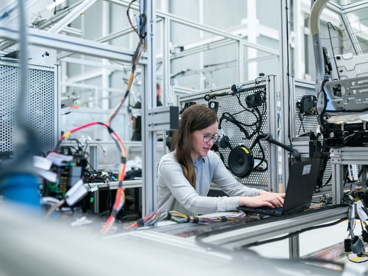 Technician working on laptop on a manufacturing production floor